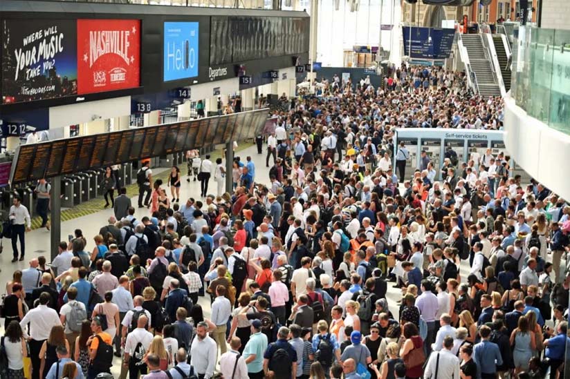 A crowd watching a station's arrivals/departures board.