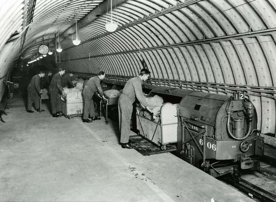 Postal workers load mail carts onto a train.