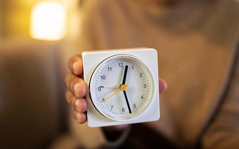 A person holds a clock.