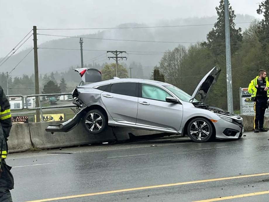 A vehicle propped up on a road barrier.