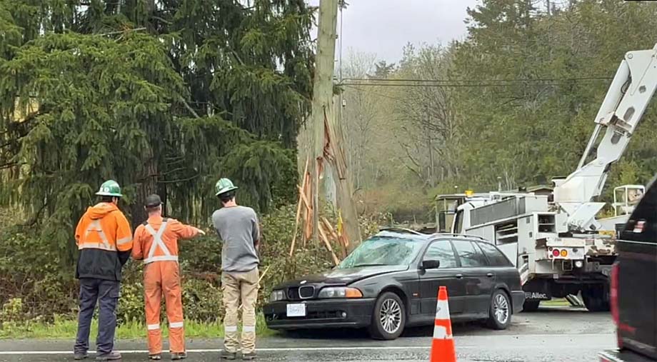 A hydro pole splintered at its base hanging precariously from the powerlines.