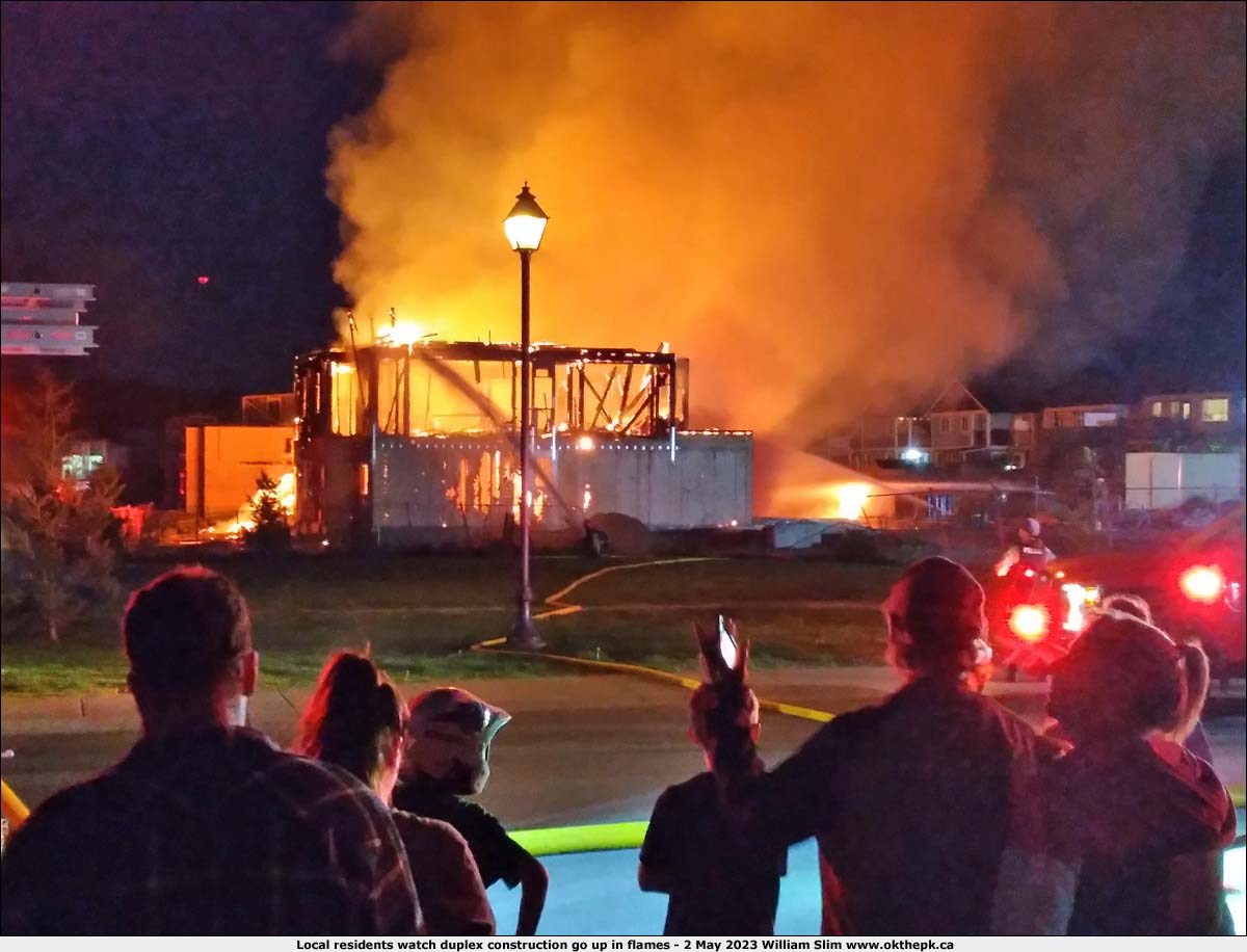 Local residents watch duplex construction go up in flames.