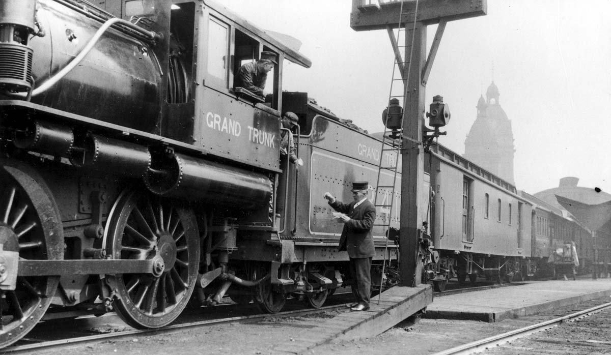 The crew checks the train orders for a Grand Trunk Railway train.