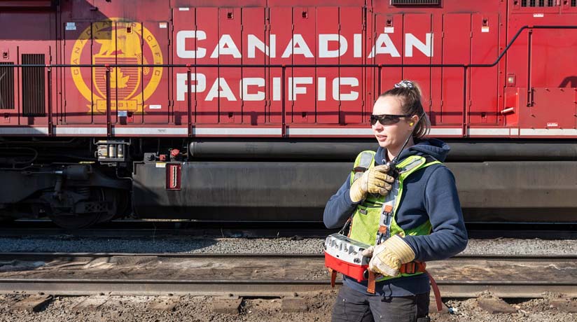 A CP employee operates a remote control locomotive from a belt pack.